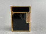 a close up of a black and gold lighter on a table