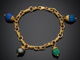 un gros plan sur un bracelet en or orné de perles bleues et vertes