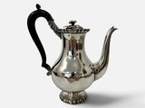 une théière ancienne en argent, avec une anse noire sur fond blanc