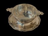 an antique silver plate with a bowl and saucer on a black background
