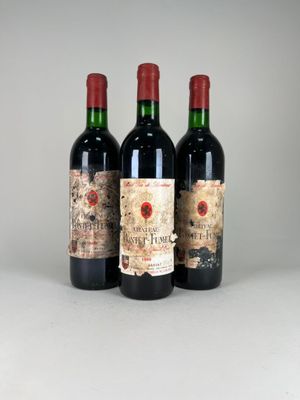 three bottles of red wine sitting on top of a white table