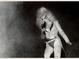 photographie en noir et blanc d'une femme aux cheveux longs chantant dans un micro