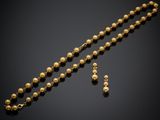 a gold beaded necklace and earrings set on a black background