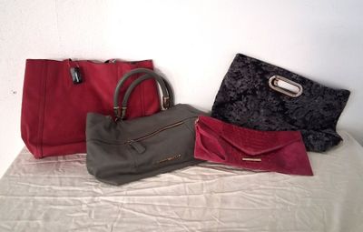 three purses sitting on a bed next to each other