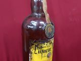 an old bottle of liquor sitting on a red surface