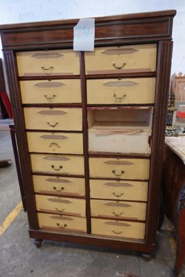 une grande armoire en bois comportant de nombreux tiroirs et surmontée de tiroirs