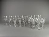 douze verres à vin en cristal alignés sur une surface grise