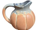 a small ceramic pitcher with a handle on a white background