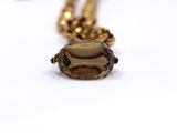 an image of a gold necklace with a smoky quartz stone on it