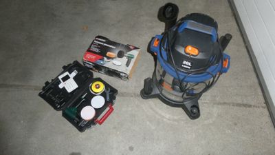 un aspirateur et d'autres outils posés par terre à côté de la porte de garage