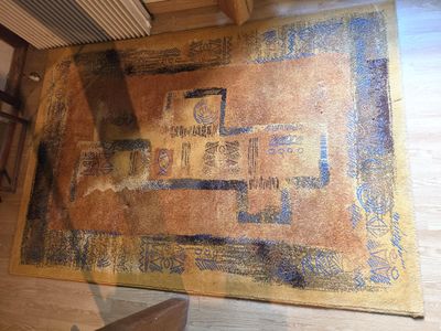 un tapis posé à même le sol, sur lequel figure l'image d'un bâtiment