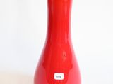 un vase rouge bordé de noir posé sur une surface blanche