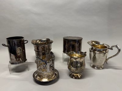 trois tasses en métal argenté et un pichet en métal argenté sur fond blanc