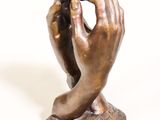 statue en bronze représentant une main tenant un téléphone portable posée sur une surface blanche
