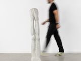 a man walking past a sculpture in a white room