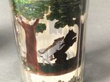 a shot glass with a picture of a bear and a tree on it