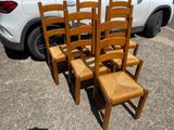 six wooden chairs sitting in a parking lot next to a car