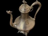 an antique silver tea pot with a bird on the handle
