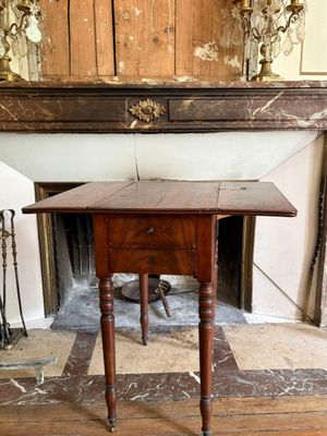une petite table munie d'un tiroir, placée devant une cheminée