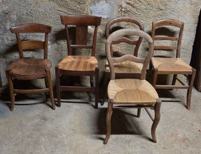 quatre chaises en bois placées les unes à côté des autres devant un mur en pierre
