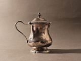 une cafetière ancienne en argent posée sur une table