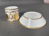 two white and gold cups sitting on top of a table next to each other