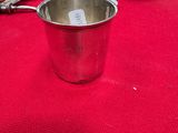 a silver cup sitting on top of a red tablecloth next to a clock