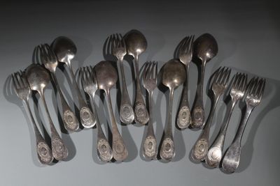 six fourchettes et six cuillères sont disposées en rangée sur une table