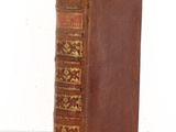 an old book with a brown cover sitting on top of a table