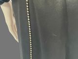 the back view of a woman wearing a black dress with a gold zipper