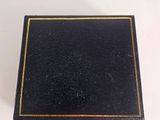 an old black book with gold trim sitting on top of a white table