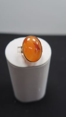 une bague en pierre orange posée sur une boîte blanche