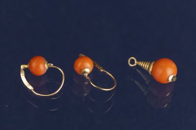 trois paires de boucles d'oreilles en or ornées de perles orange sur un fond noir