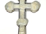 une croix blanche ornée de sculptures, se détachant sur un mur blanc