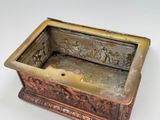 a small metal box with carvings on it on a white surface