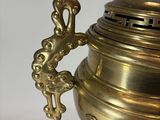 a large brass urn with a lion on top of it