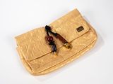un sac à main doré muni d'une poignée en bois, posé sur une surface blanche