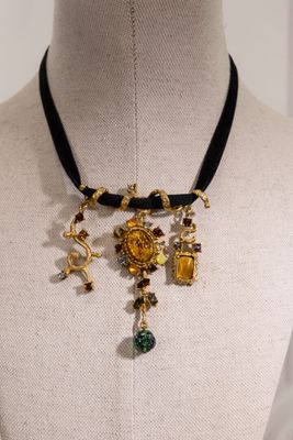 Collier doré et noir orné de breloques, présenté sur un mannequin