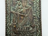 a close up of a metal plaque with a ship on it