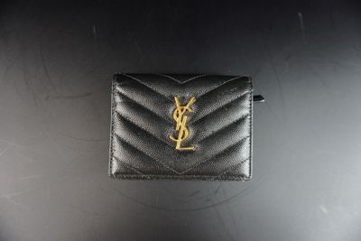 un petit portefeuille noir orné d'un logo YSL doré