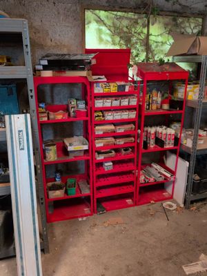 a red shelving in the middle of a room filled with items