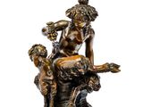 une statue antique en bronze représentant une femme assise sur un rocher avec deux enfants