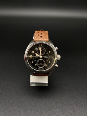 une image représentant une montre avec un bracelet en cuir marron sur un fond noir
