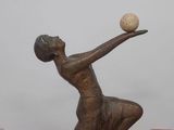 a statue of a woman playing with a ball on a table