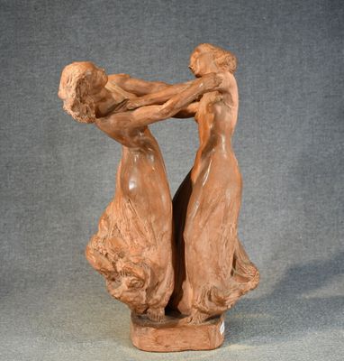 sculpture of two women holding hands on a wooden base