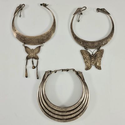 trois bijoux en argent posés sur une surface blanche