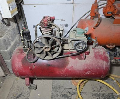 a red air compressor sitting on top of a red tank