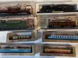 six modèles réduits de trains différents, dans des sachets en plastique, posés sur une table