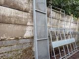 a bunch of metal chairs leaning against a concrete wall