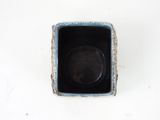 a small square bowl with a black lid on a white surface